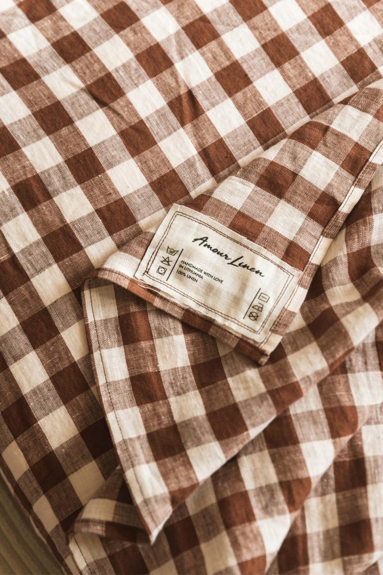 Mocha Gingham linen flat sheet styled on a bed, showcasing its soft texture and rustic checkered pattern